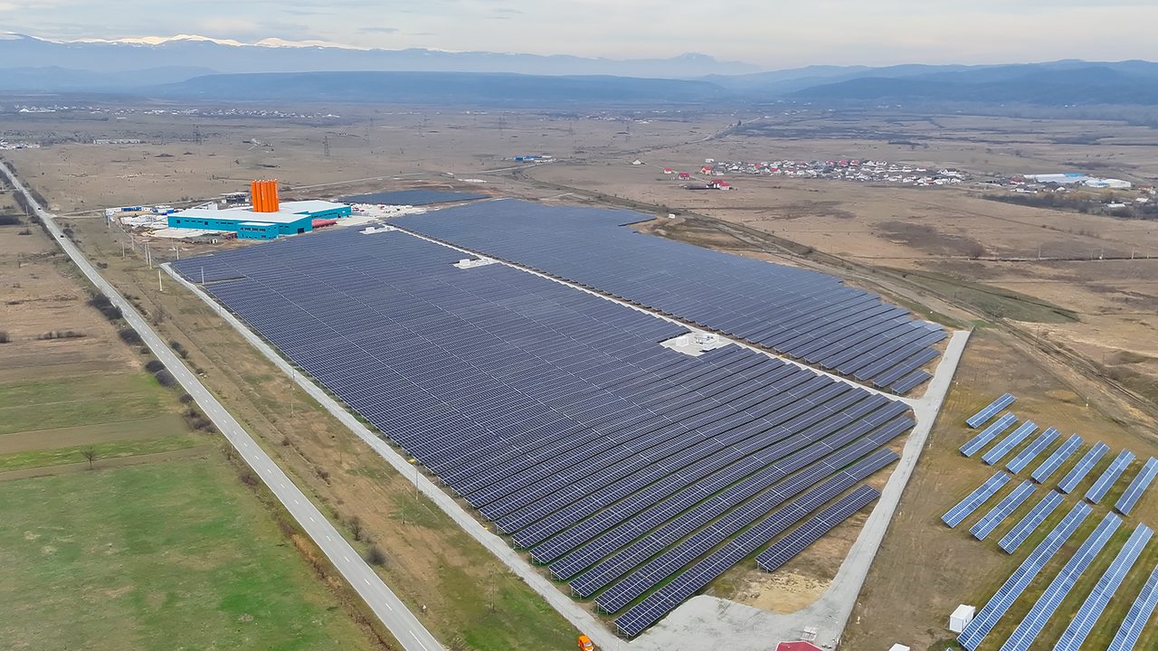 Aerial drone view of the Enexus solar power plant in Romania, with module rows and the site building visible